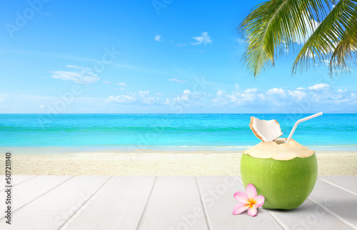Fototapeta Naklejka Na Ścianę i Meble -  Coconut  juice on wooden table with beach and blue sky background.