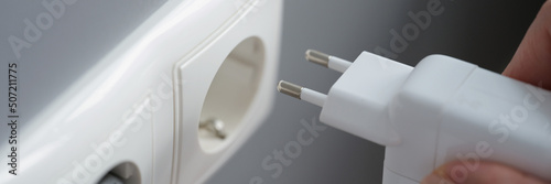 Foto Hand inserts laptop power supply into the socket