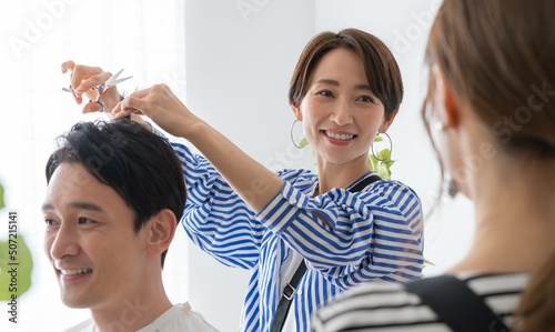 アシスタントにヘアカットを教える女性美容師