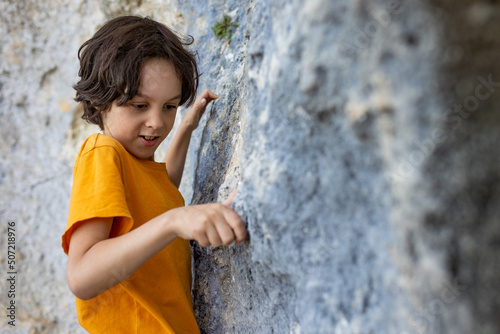 A little rock climber is training to climb a boulder