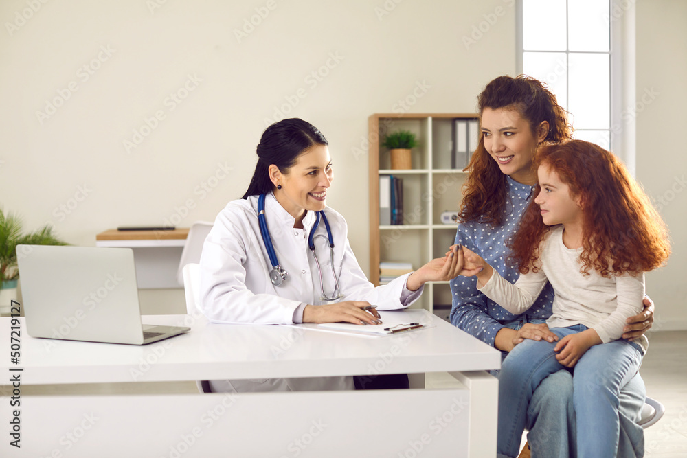 Mom and her preteen daughter came for regular annual pediatric checkup at modern hospital. Friendly female doctor in office holding hand of little girl encourages her girl before medical examination. Mom and her preteen daughter came for regular annual pediatric checkup at modern hospital. Friendly female doctor in office holding hand of little girl encourages her girl before medical examination.
