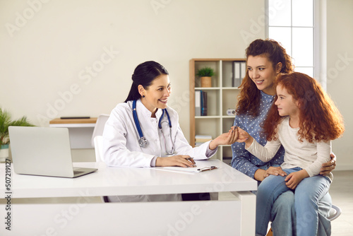 Mom and her preteen daughter came for regular annual pediatric checkup at modern hospital. Friendly female doctor in office holding hand of little girl encourages her girl before medical examination.