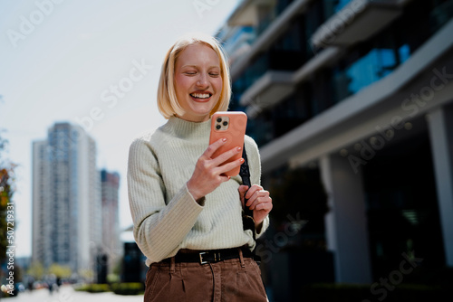 Young woman reading a message on the phone in the city. photo