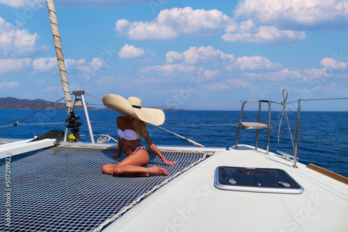 Beautiful young blond woman in bikini sitting on catamaran at sunny summer day © Anatoly Repin