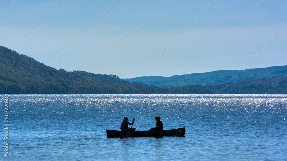 Coniston, United Kingdom - 21st April 2022 : A rowing boat silhouetted on Coniston Water