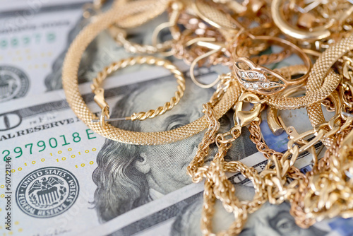 Many expensive golden jewerly rings, earrings and necklaces with big amount of US dollar bills on white background. Pawnshop or jewerly shop photo