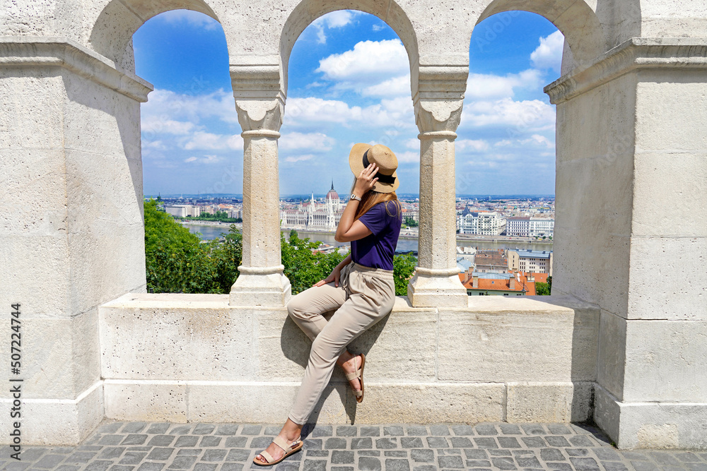 Beautiful woman enjoying cityscape with Hungarian Parliament Building and Danube River from Fisherman's Bastion in Budapest, Hungary