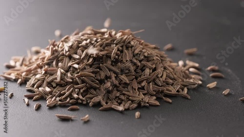 4K. Cumin Seeds rotating on turntable on a slate background. Seasoning cumin or jeera, a lot of seeds rotating. Pouring caraway seeds on a stone table. Spices for cooking food. cooking ingredients