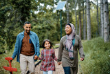 Happy Middle Eastern family holding hands while walking through park.