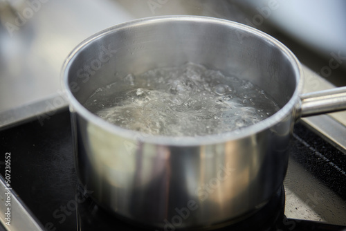 boiling water in a saucepan on an electric stove, close-up, boiling water in a saucepan close-up. Boiling water in pan on electric stove in the kitchen with smoke
