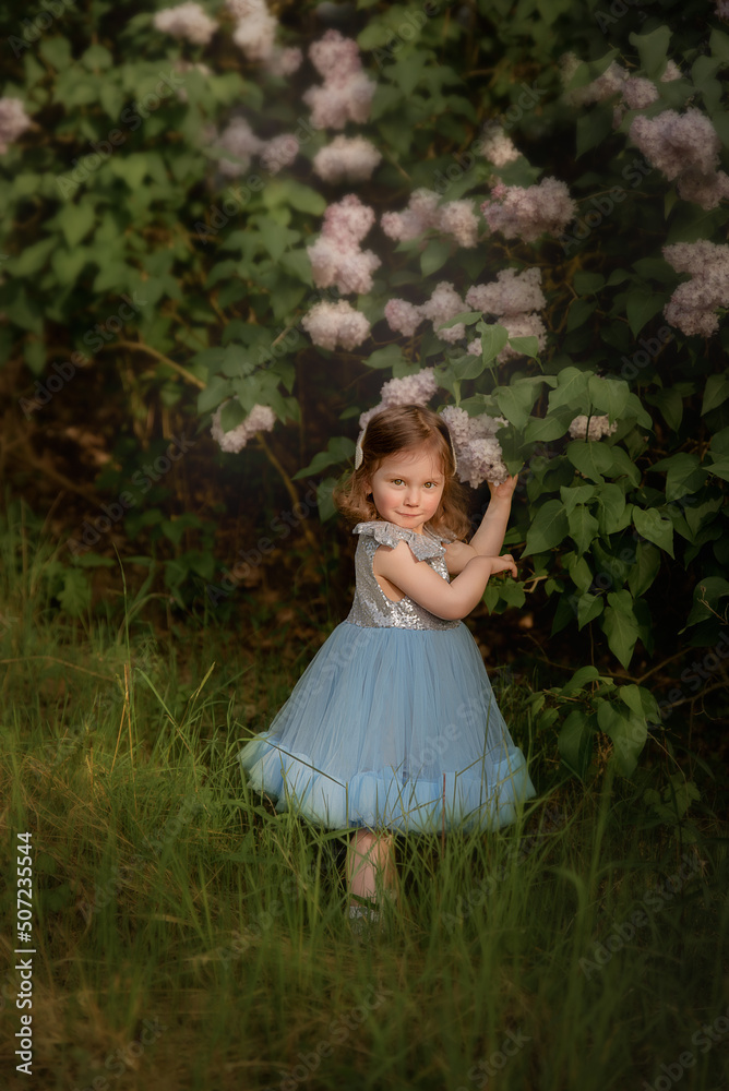 a child in a blue dress plays in the park. plays in the forest. girl with a basket collects flowers.
