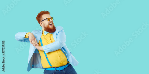 Фотография Cheerful fashionable and stylish bearded chubby man having fun on vivid light blue background