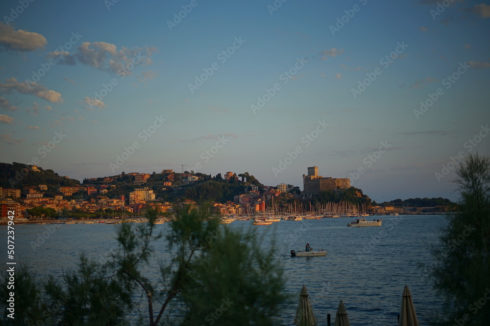 Lerici, Italy - 08 08 2020: Golfo dei Poeti, People on thebeach at sunset. Romantic Ligurian beach with a castle in the distance. Village of Tellaro, place of inspiration for the writer Mary Shelley.