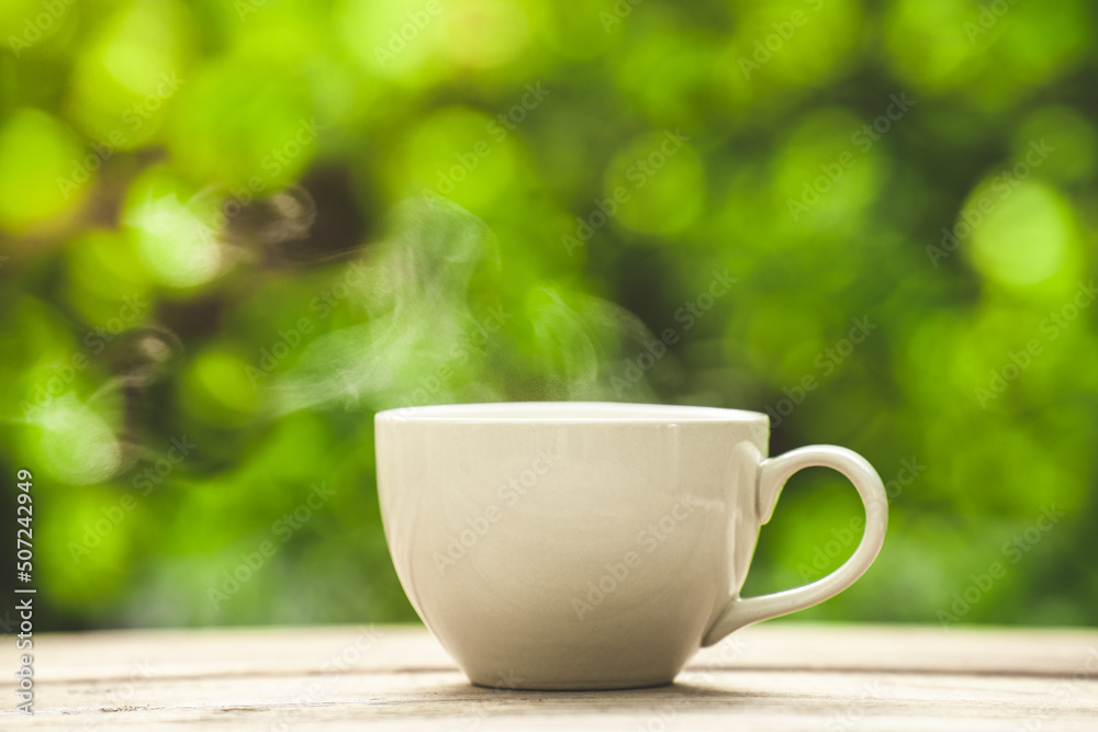 white ceramic coffee mug On the wooden floor, green tree bokeh background.