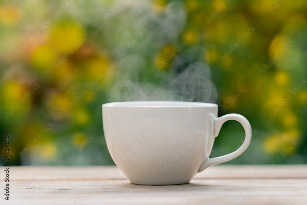 white ceramic coffee mug On the wooden floor, green tree bokeh background. white ceramic coffee mug On the wooden floor, green tree bokeh background.