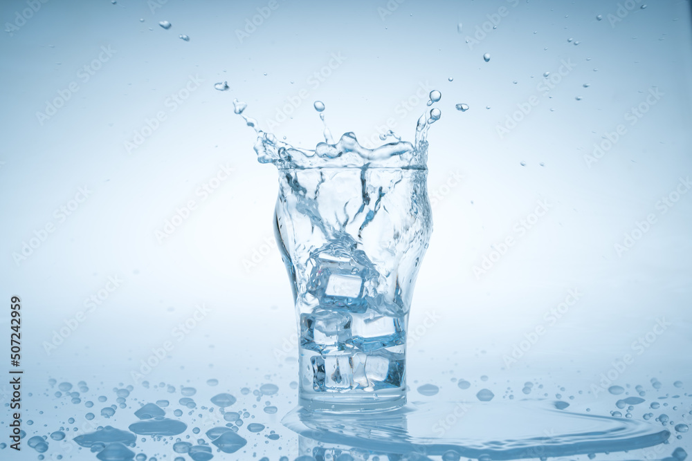 Ice cube fell into the glass of water. Water splashed from the clear glass. Fresh concept Ice cube fell into the glass of water. Water splashed from the clear glass. Fresh concept