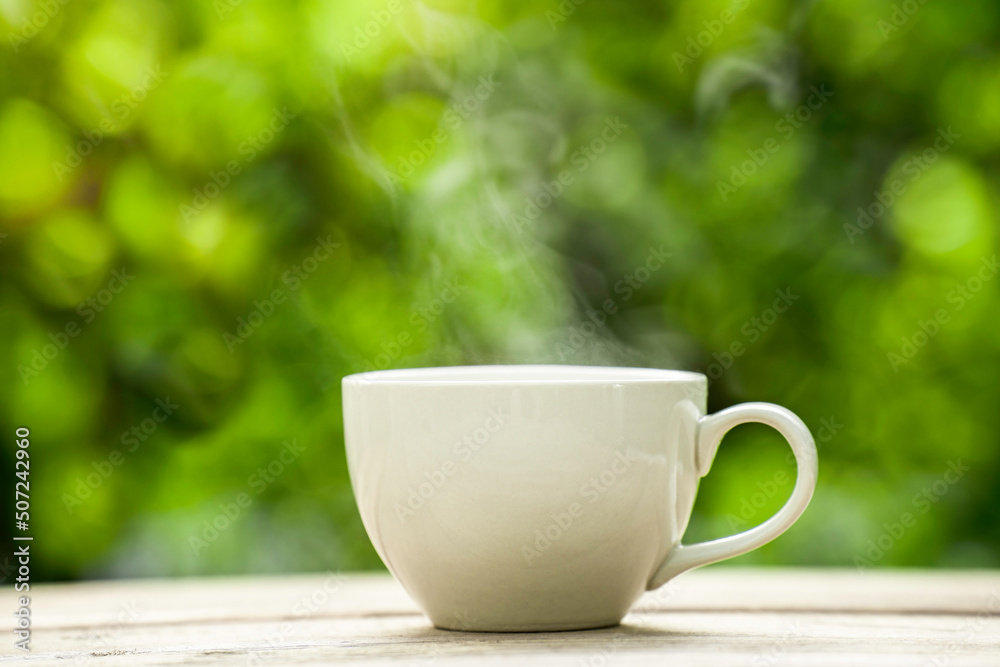 white ceramic coffee mug On the wooden floor, green tree bokeh background. white ceramic coffee mug On the wooden floor, green tree bokeh background.