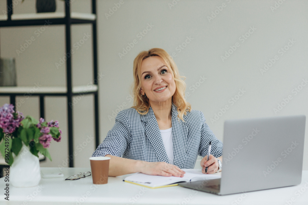 Close-up portrait of smiling senior mature middle aged businesswoman using laptop working. Woman 50s