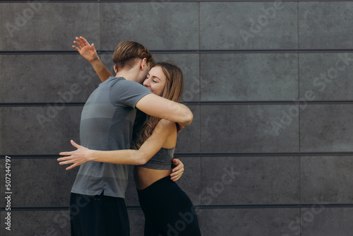 Fit beautiful woman and handsome muscular man after outdoor training, hugging and smiling. Couple. Healthy, sporty lifestyle concept. Real people emotions