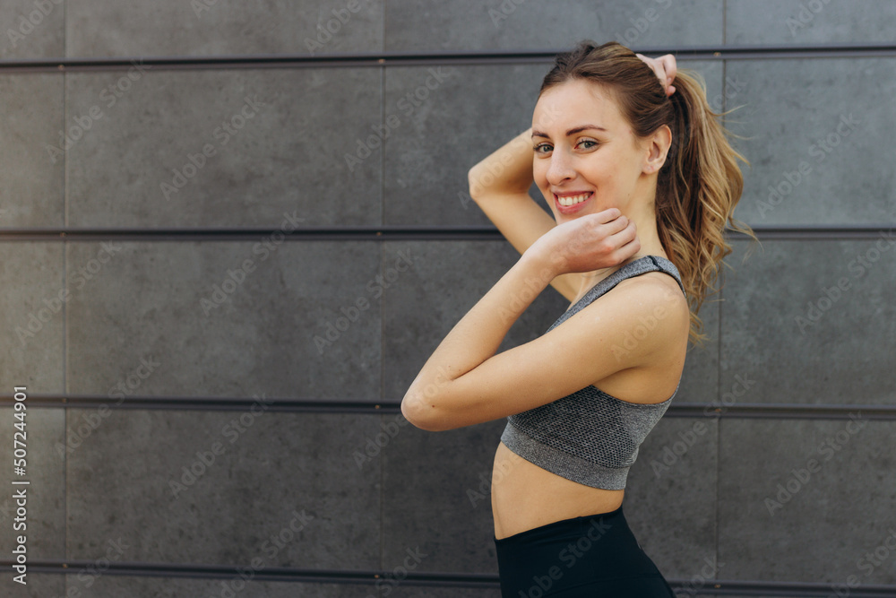 Portrait of beautiful fitness woman smiling and looking at camera isolated on black wall. Happy fit girl on gray wall with copy space. Portrait of beautiful fitness woman smiling and looking at camera isolated on black wall. Happy fit girl on gray wall with copy space.