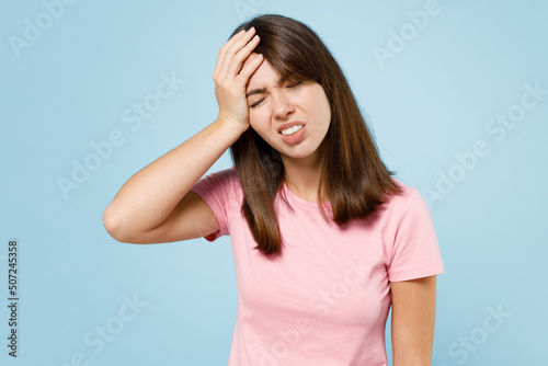 Young sad caucasian woman 20s wearing pink t-shirt put hand on face facepalm epic fail mistaken omg gesture isolated on pastel plain light blue background studio portrait. People lifestyle concept