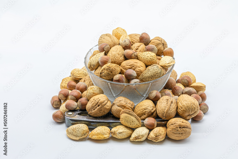 Glass bowl full of walnuts with a nutcracker isolated on a white background Glass bowl full of walnuts with a nutcracker isolated on a white background