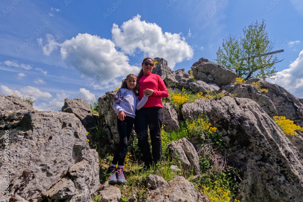 Portrait of mother and child on the peaks of the rocks. Family nature hiking adventure. Sunny spring day. Active lifestyle. 
