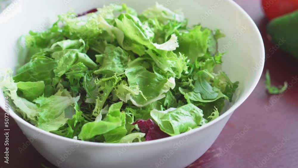 Cooking healthy food in the kitchen. Fresh vegetable salad. Vegetarian diet. Close up of healthy lunch with radishes, tomatoes, lettuce, fragrant herbs and olives. Woman cuts and mixes salad. Cooking healthy food in the kitchen. Fresh vegetable salad. Vegetarian diet. Close up of healthy lunch with radishes, tomatoes, lettuce, fragrant herbs and olives. Woman cuts and mixes salad.