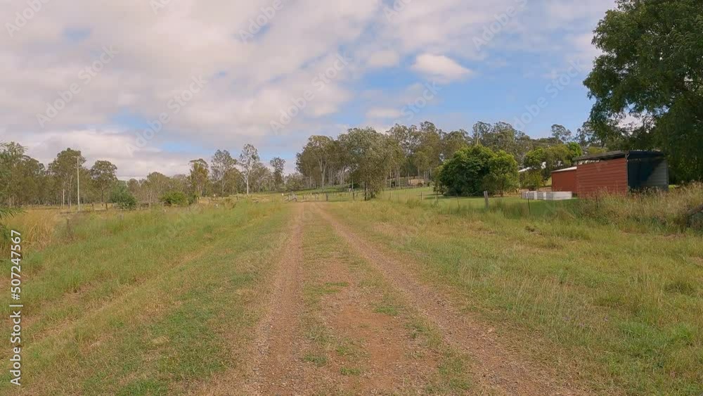 Point of View of hikers bushwalking old rail line, raised edges, gravel pathway, old sheds and trees along, Brisbane Valley Rail Trail, Qld 4K