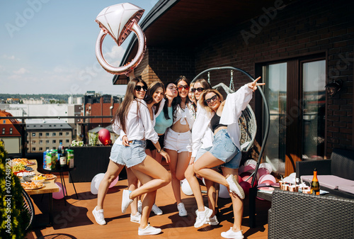 Happy and cheerful group of women friends together dancing and having fun on the rooftop at home. Bachelorette party.