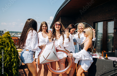 Happy and cheerful group of women friends together dancing and having fun on the rooftop at home. Bachelorette party.