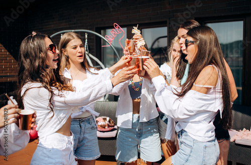 Happy and cheerful group of women friends together dancing and drink champagne on the rooftop at home. Bachelorette party.