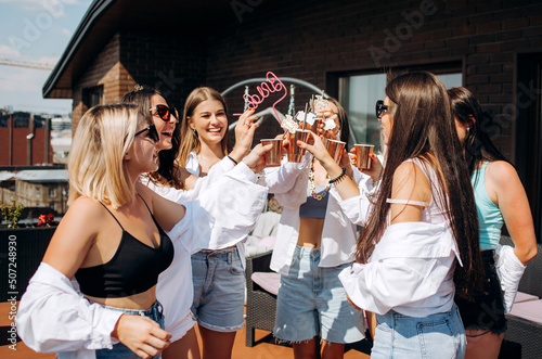 Happy and cheerful group of women friends together dancing and drink champagne on the rooftop at home. Bachelorette party.