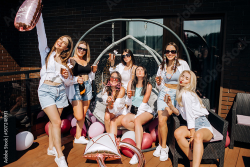 Fototapeta Naklejka Na Ścianę i Meble -  Happy and cheerful group of women friends together dancing and drink champagne on the rooftop at home. Bachelorette party.