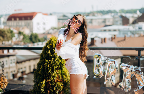Happy bride celebrates bachelorette party, dancing and having fun on the roof of the house.