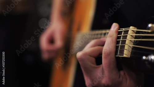 A young man tunes an acoustic guitar plucking the strings and musical notes