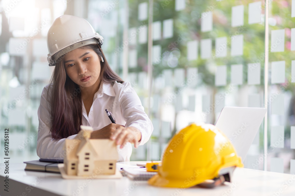 Female architect designer in an office working on a laptop is modeling a house and writing a housing project. Female architect designer in an office working on a laptop is modeling a house and writing a housing project.