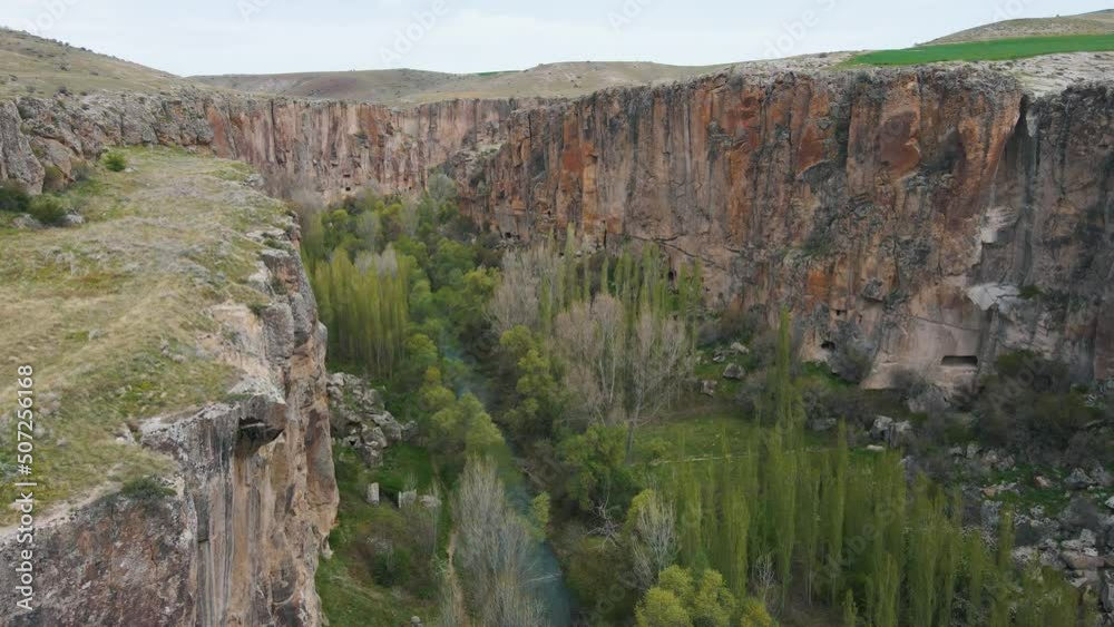 Aerial drone shot over river passing through Ihlara Canyon in Cappadocia, Turkey on a cloudy day. Aerial drone shot over river passing through Ihlara Canyon in Cappadocia, Turkey on a cloudy day.