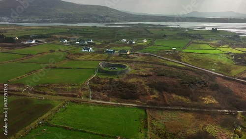 Cahergal Ringfort, Kerry, Ireland, March 2022. Drone slowly orbits the ancient stone monument clockwise from the north while ascending with Ballycarbery Castle and Valentia Harbour in the distance. photo