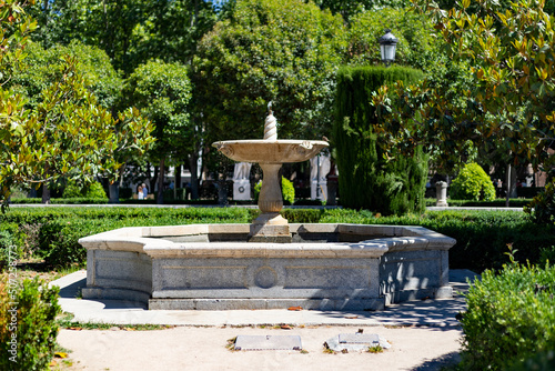 Fountain. Stone fountain surrounded by green vegetation in a park in Madrid on a clear day with a blue sky, in Spain. Europe. Photography.