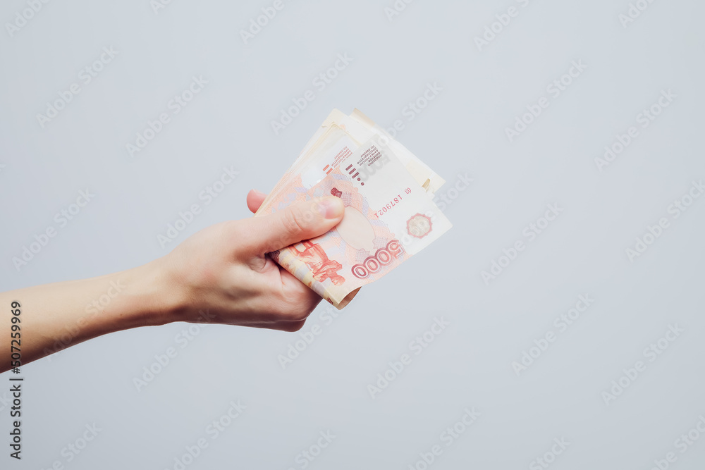 A hand holds a stack of five thousandth bill folded in half on a white background. Finance concept A hand holds a stack of five thousandth bill folded in half on a white background. Finance concept