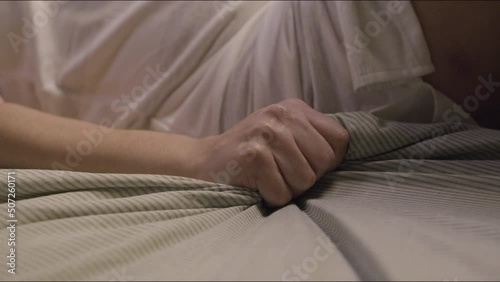 Unrecognizable pregnant woman clutching blanket in hand in pain. Expecting mother lying on bed, feeling pain, having contraction at home. Parenthood, medicine, pregnancy, emotion concept