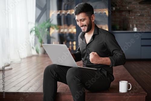 happy business owner looking at his laptop screen.