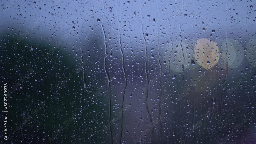 Moody rain on window during storm with bokeh traffic lights