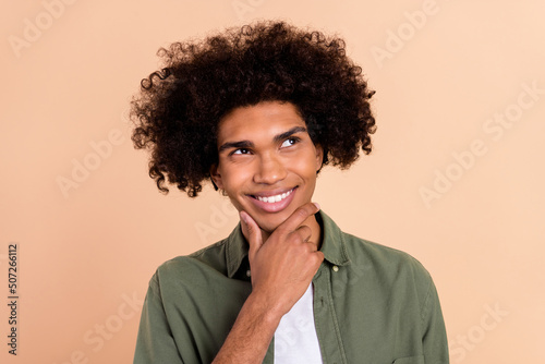 Portrait of attractive bewildered cheerful wavy-haired guy touching chin brainstorming isolated over beige pastel color background