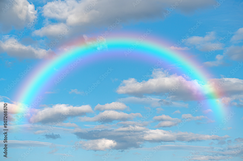 rainbow. Stunning blue sky rainbow big fluffy clouds with giant arcing rainbow against beautiful summer time blue sky with copy space for messages