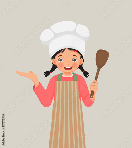 cute little girl in chef hat and apron holding cooking utensil spatula with hand showing for copy space