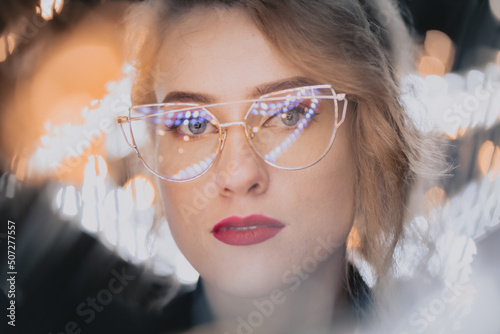 Nowoczesny portret dziewczyny w okularach wśród lampek bokeh photo