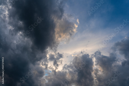 Dark gray clouds fly across the sky. Puffy fluffy grey clouds at spring day during sunset