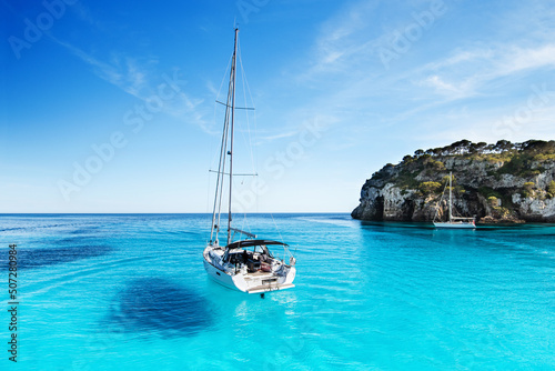 Fototapeta Naklejka Na Ścianę i Meble -  Beautiful beach with sailing boat yacht, Cala Macarelleta, Menorca island, Spain. Yachting, travel and active lifestyle concept